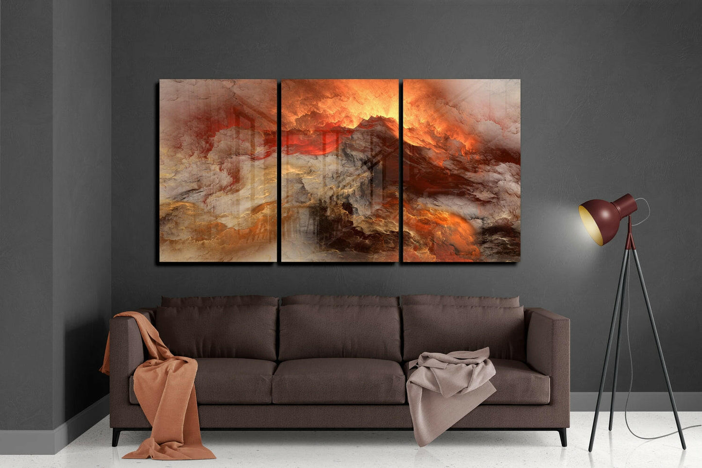 Three-panel volcano glass wall art displaying fiery orange and golden lava landscapes above brown sofa in modern living room.