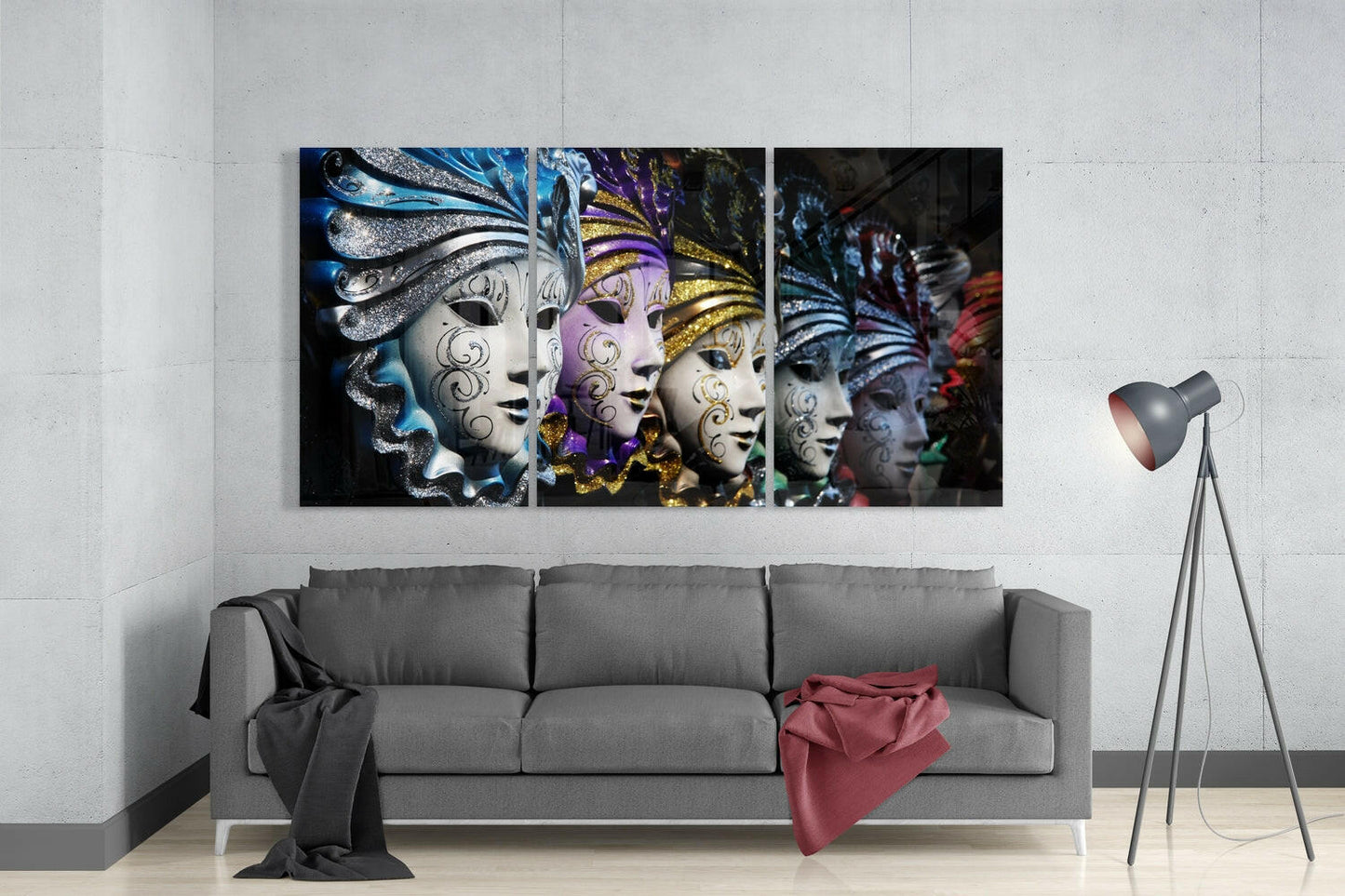Triptych glass wall art displaying ornate Venetian masks with blue, purple, and gold embellishments mounted above gray sofa in modern living room.