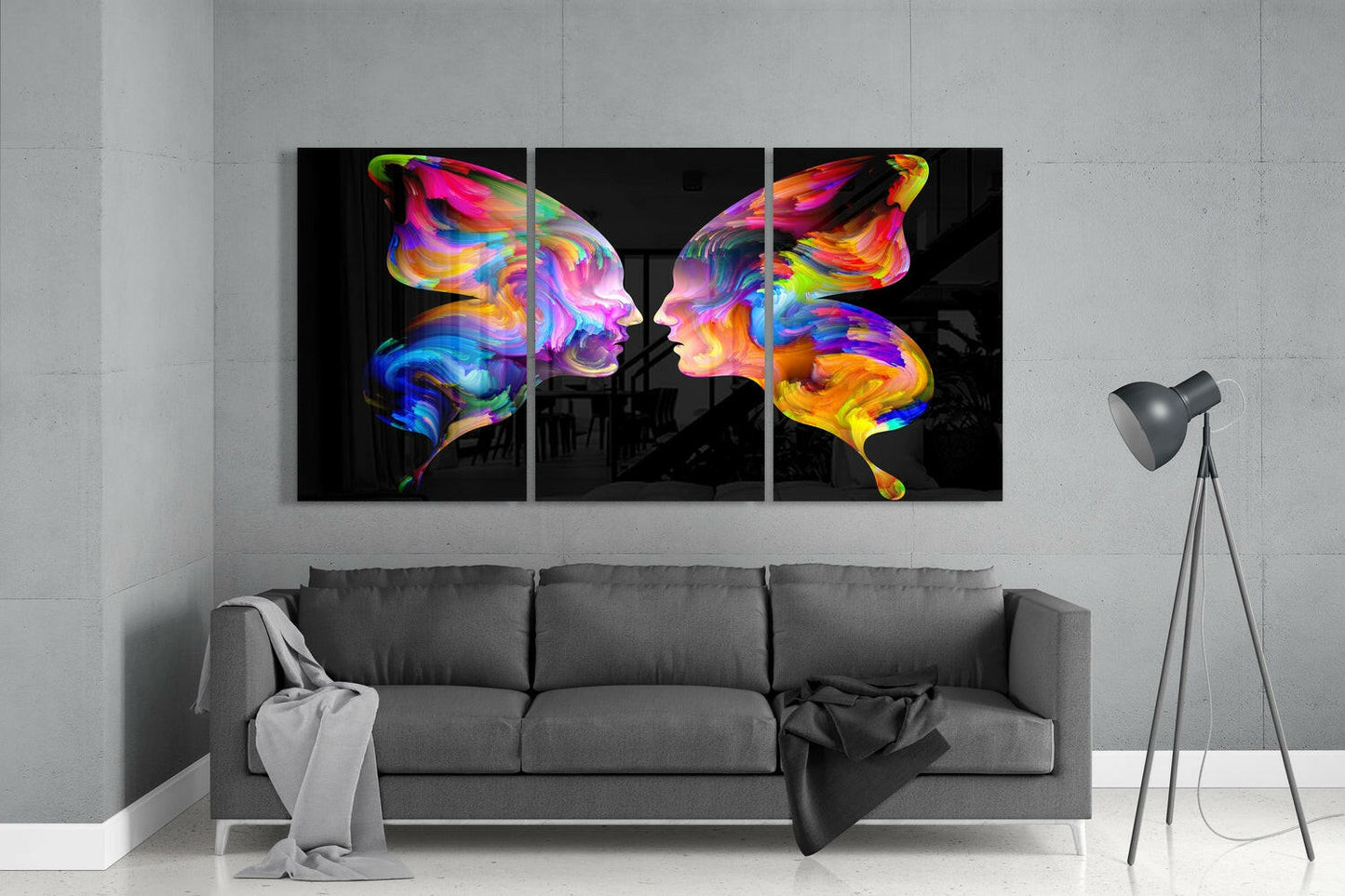 Vibrant three-panel glass wall art with colorful butterfly silhouettes displayed above gray sofa in modern room.