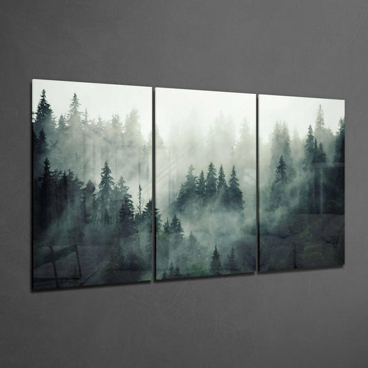 Three-panel glass wall art displaying misty forest landscape with evergreen trees in shades of green and gray against textured gray wall.