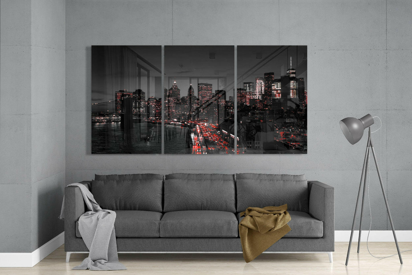 Three-panel glass art depicting a nighttime cityscape with illuminated buildings and red traffic lights, displayed above a gray sofa in a modern living room.