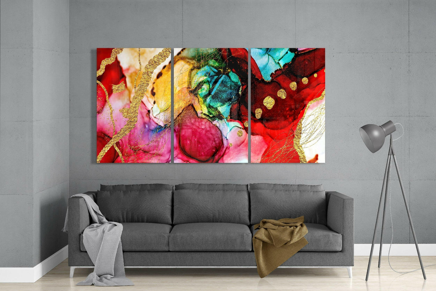 Three colorful glass art panels with red, pink, gold, turquoise, and yellow hues displayed above gray sofa in modern living room.