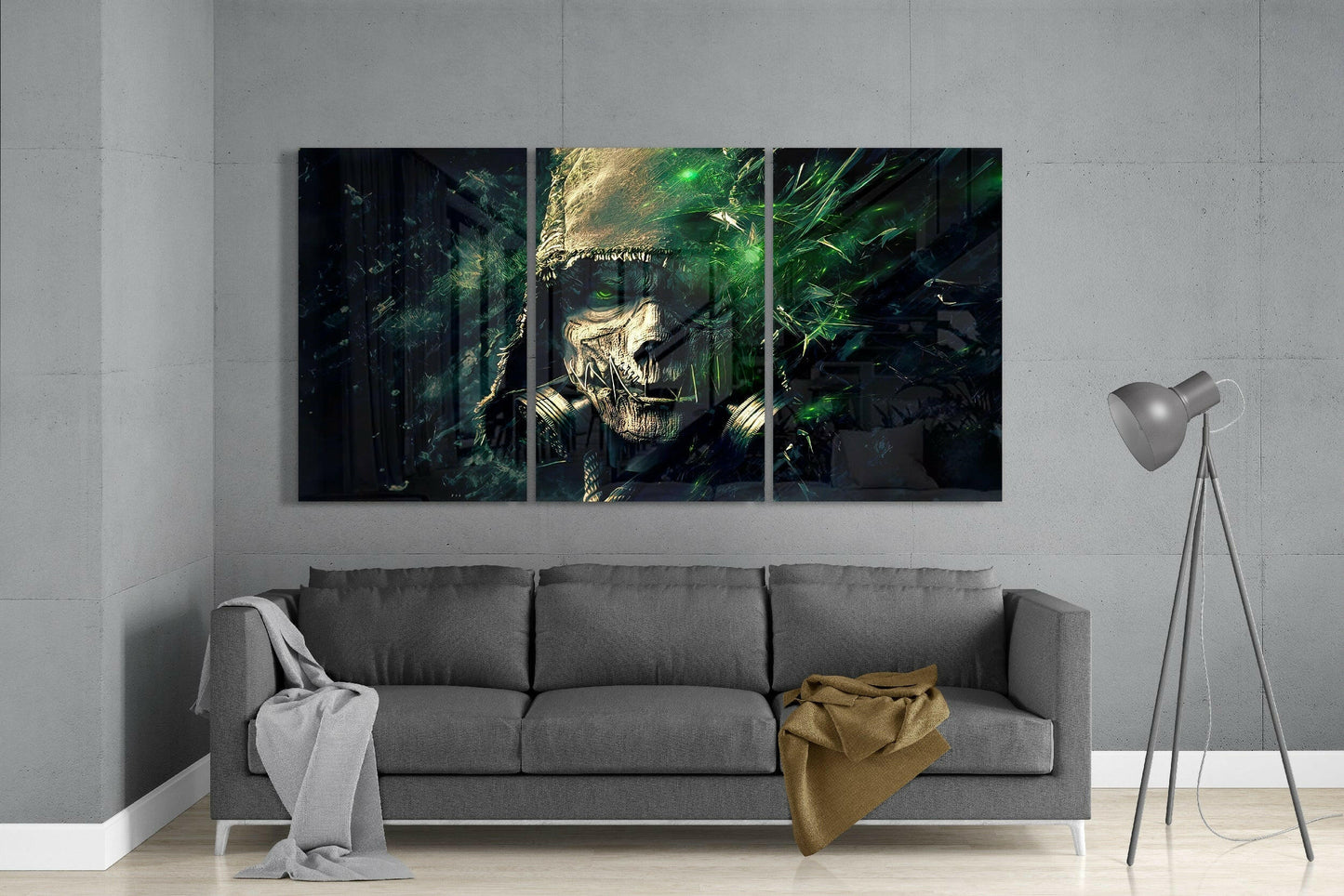 Three-panel glass art depicting a skull with green glowing eyes and vines displayed above gray sofa in modern living room.