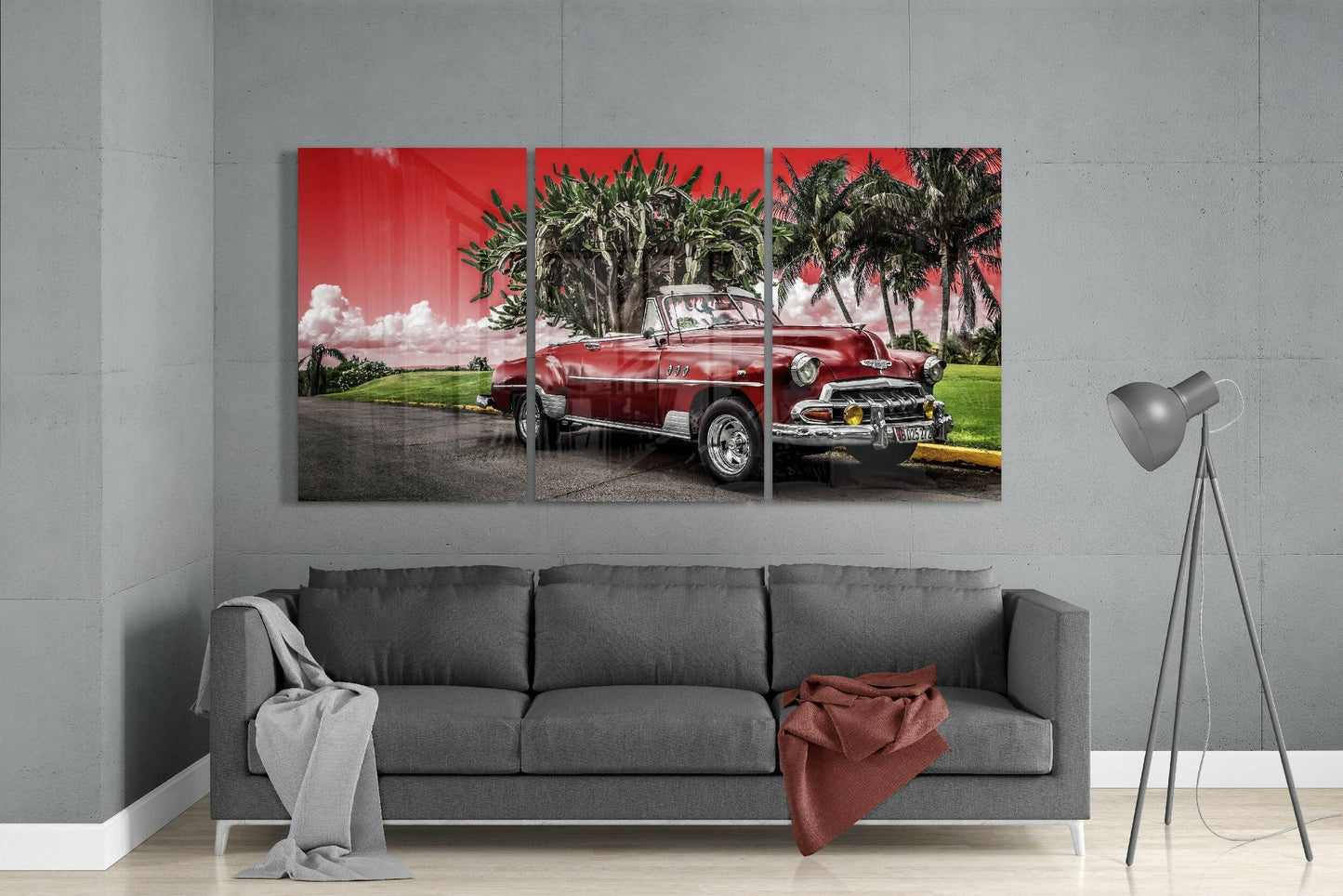 Three-panel red classic car glass art displayed above gray sofa in modern living room interior.