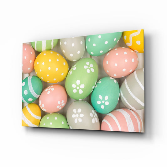 Angled view of colorful Easter eggs with polka dots and floral patterns in yellow, green, pink, and cream displayed on glass wall art.