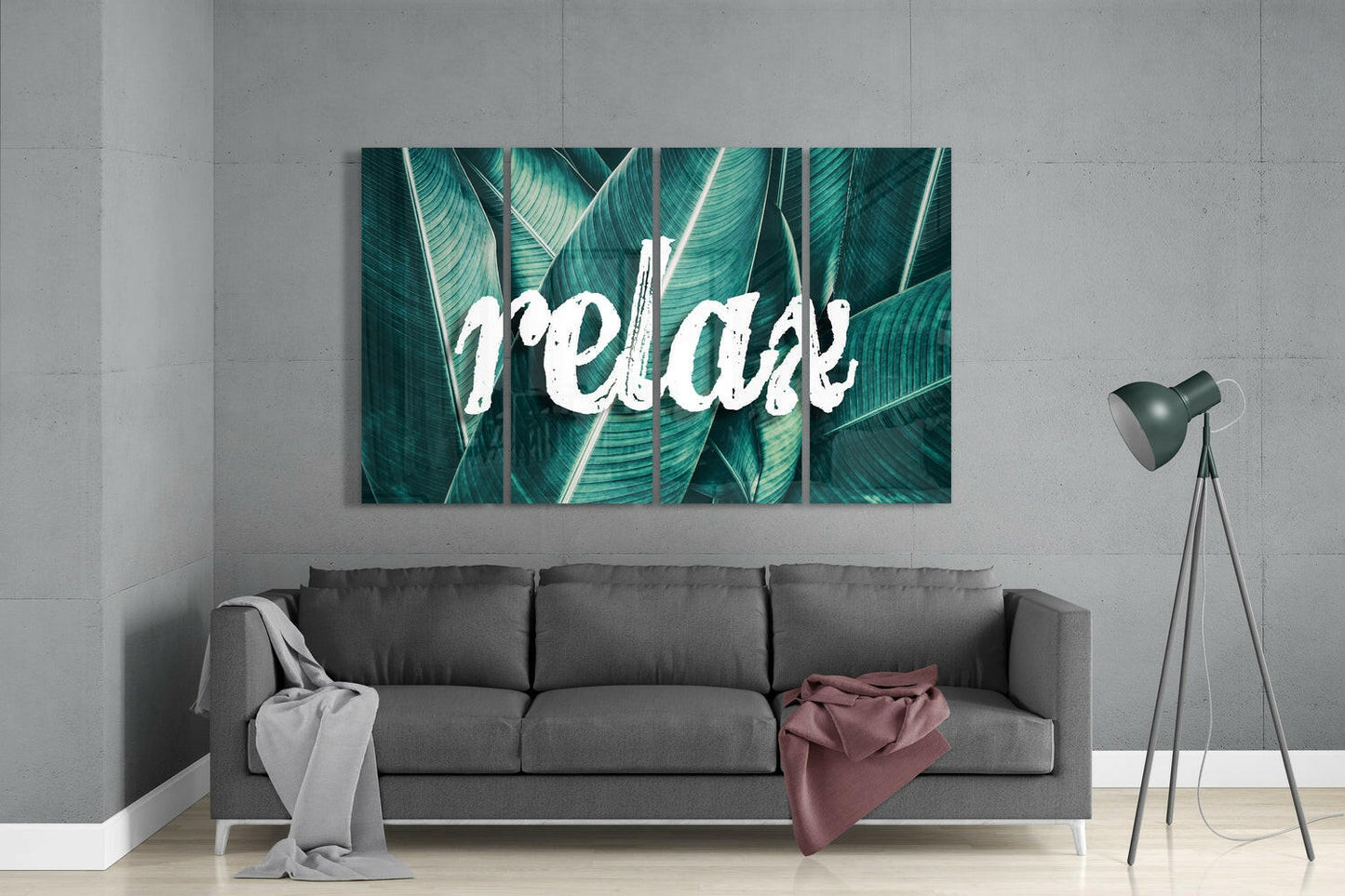 Four-panel glass wall art with white "Relax" text overlaid on teal and green striped tropical leaves, displayed above gray sofa in modern living room.