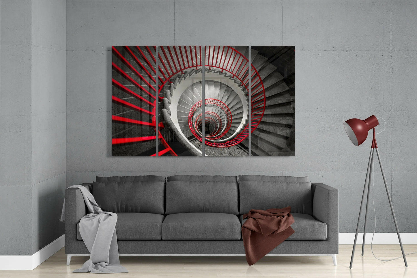 Four-panel glass wall art depicting a spiral staircase with red railings receding into darkness, displayed above a gray sofa in a modern living room.