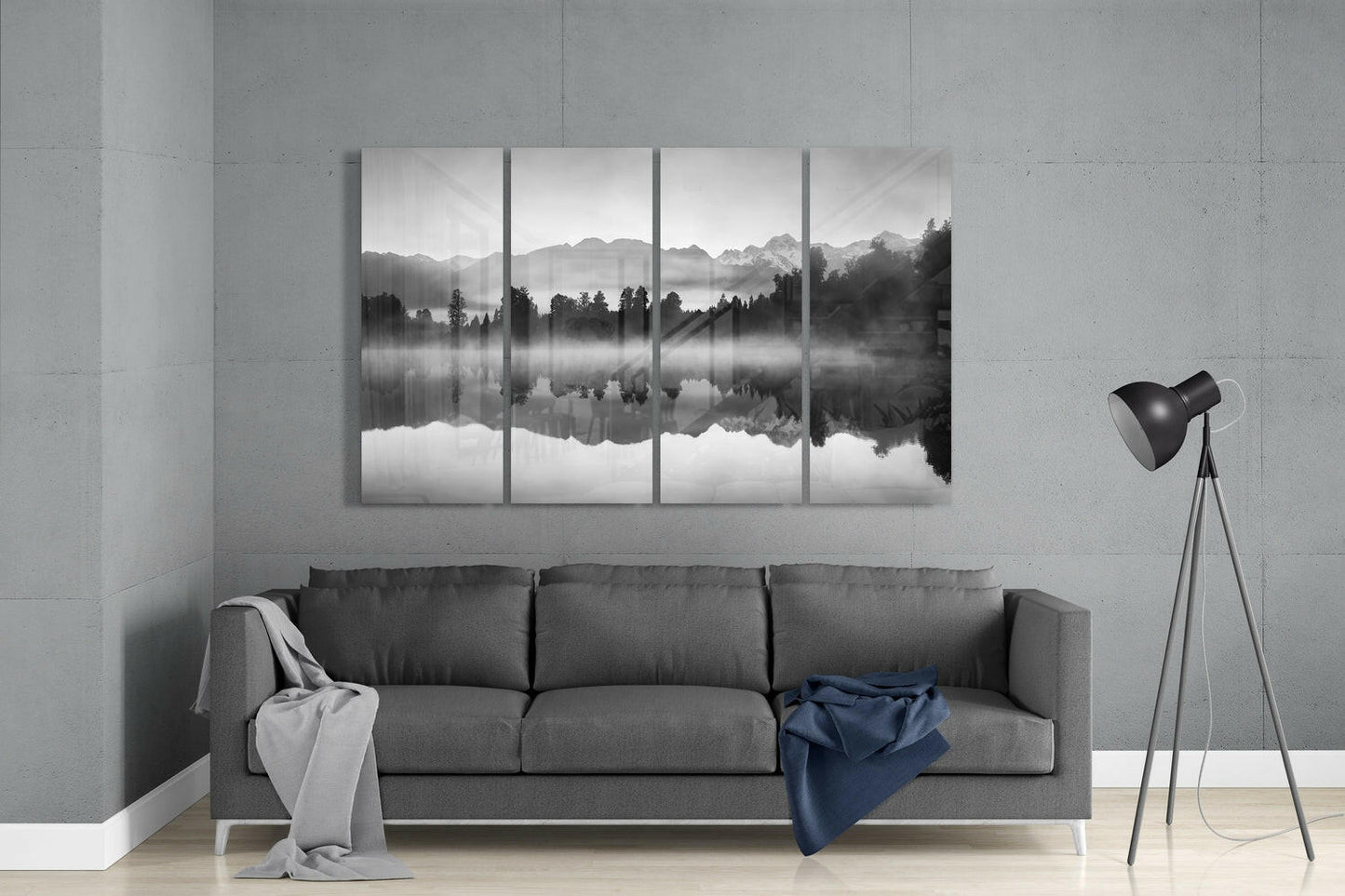 Four-panel black and white glass wall art depicting misty mountains and forest reflected in still water, displayed above gray sofa in modern living room.