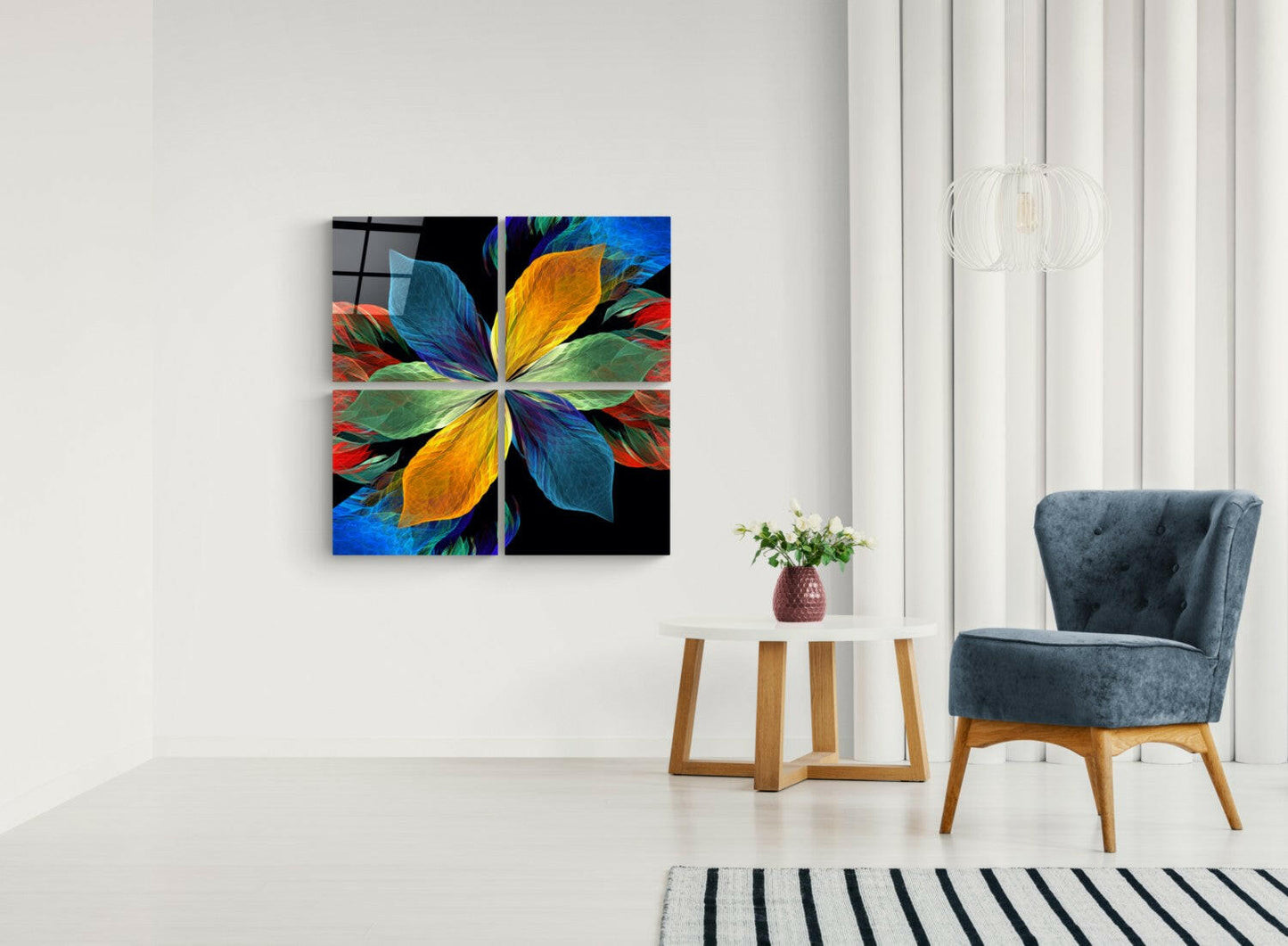 Colorful four-panel glass wall art depicting a radial flower design in blue, yellow, green, and red displayed above a side table in a minimalist interior.