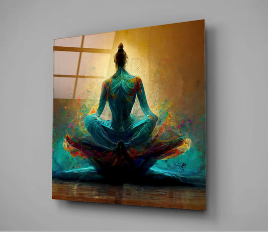Square glass wall art mounted at an angle displaying a meditating figure in turquoise with colorful energy patterns on a golden background.