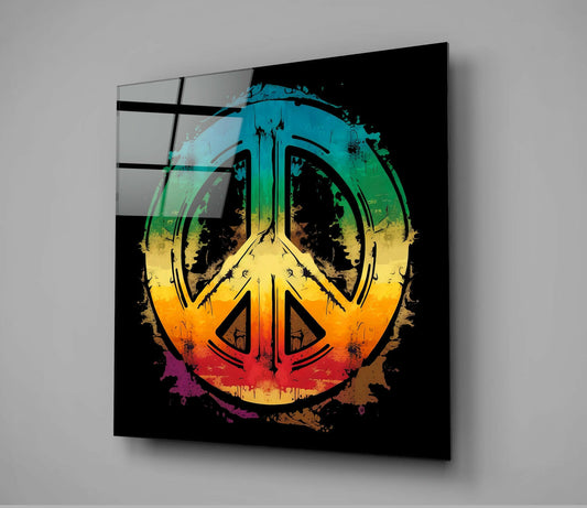 Rainbow gradient peace symbol with grunge splatter effects on black glass panel displayed at angle against gray wall.
