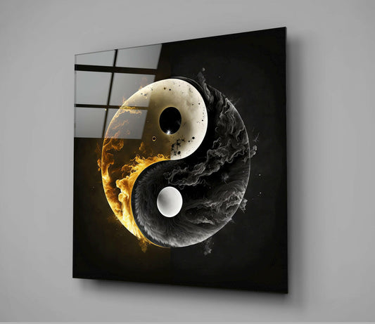 Modern glass wall art panel displaying a yin-yang symbol with golden flames on white half and black smoke on dark half, mounted at angle against gray wall.