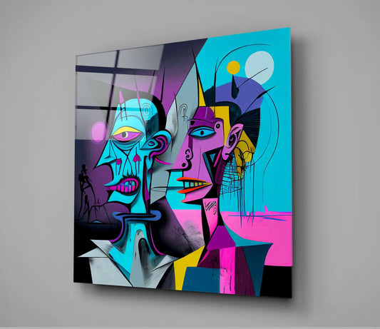 Angled view of glass wall art displaying two stylized neon-colored cubist faces in cyan, magenta, yellow, and black against gray background.