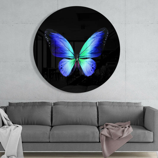 Round black glass wall art featuring a blue and green butterfly displayed above a gray sofa in a modern interior.