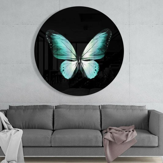 Turquoise and white butterfly wall art on black glass circle mounted above gray sofa in modern interior.