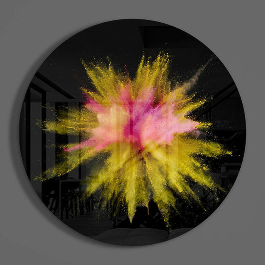 Circular black glass wall art with a vibrant yellow and pink powder explosion radiating from the center.
