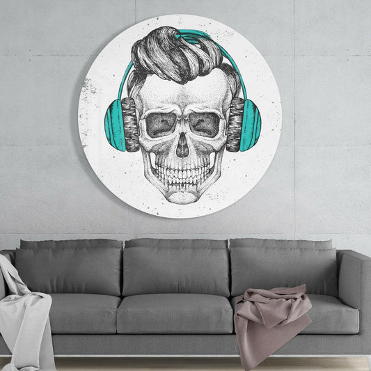 Circular glass wall art featuring a detailed pen-drawn skull wearing teal headphones and sunglasses, mounted above a gray sofa in a minimalist interior.