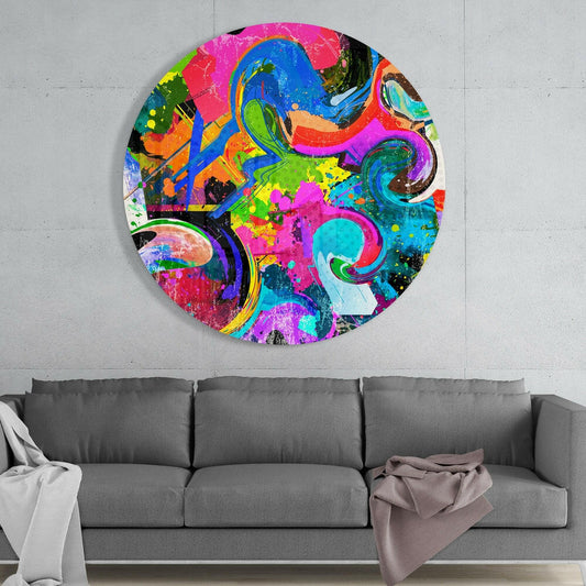 Vibrant circular glass wall art with swirling blue, pink, green, and orange patterns hung above a gray sofa against white wall.