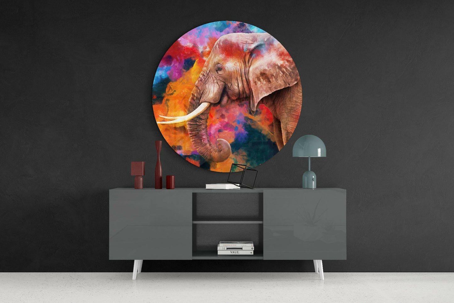 Colorful circular glass wall art depicting an elephant with vibrant watercolor background, displayed above a gray media console in modern interior setting.