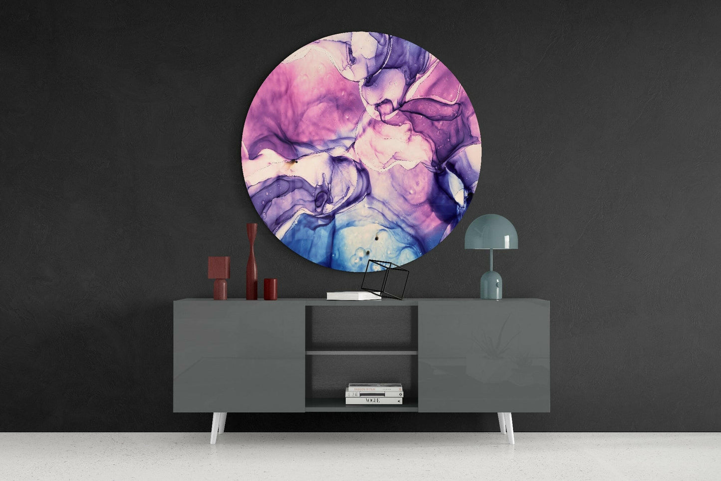 Round pink and purple marble glass wall art displayed above a gray sideboard with red candles and a teal lamp.