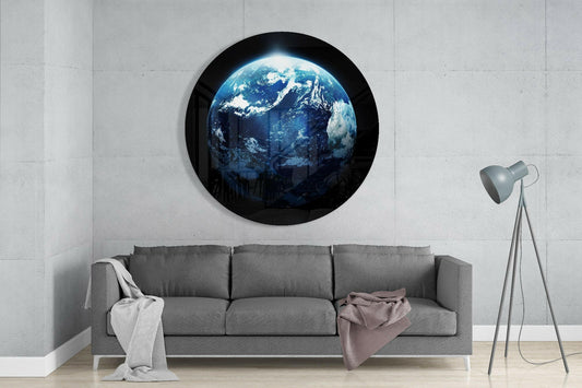 Circular glass wall art depicting Earth with blue oceans and white clouds mounted above a gray sofa in a minimalist interior.