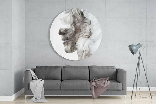 Circular glass wall art displaying a gray smoke-effect male profile portrait mounted above a gray sofa in a minimalist living room.