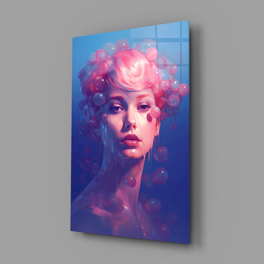Glass wall art panel displayed at an angle showing a portrait of a woman with pink hair and floating bubbles against a blue gradient background.