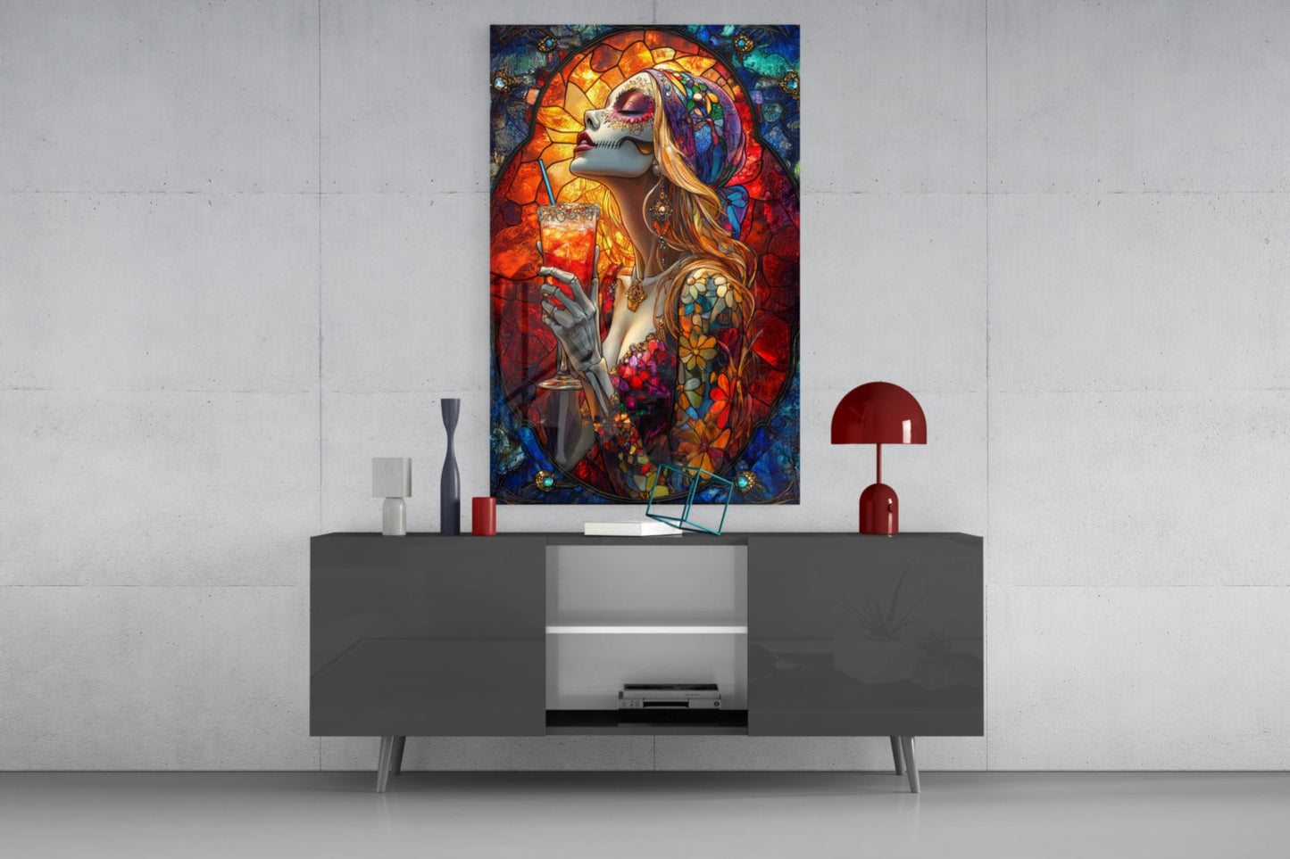 Vibrant stained glass-style wall art depicting a skull-faced woman with flowing hair and colorful tattoos holding a cocktail, displayed above a modern gray media console.