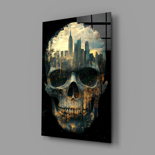 Black glass panel displaying double-exposure skull with cityscape skyline visible through eye sockets, mounted on gray wall.