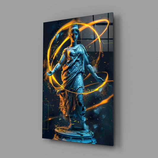 Angled view of glass wall art displaying blue classical statue surrounded by glowing yellow and orange neon orbital rings on dark background.