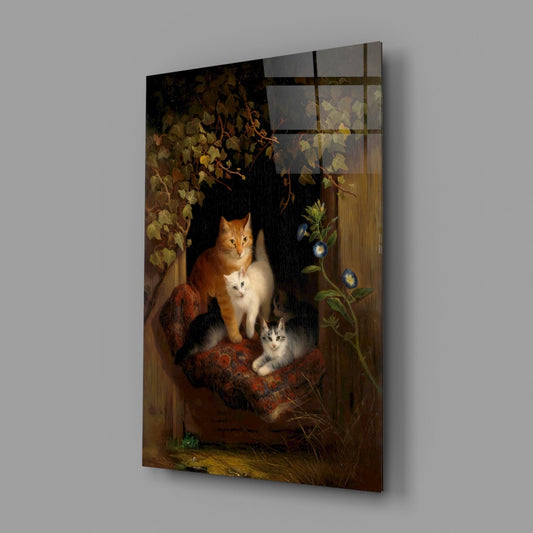 Angled view of glass wall art depicting an orange and white cat with two kittens on a wooden surface, surrounded by autumn foliage and flowering vines against a dark background.