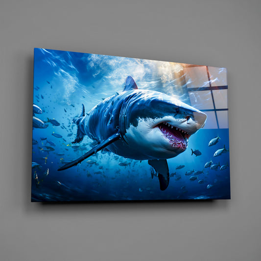 Glass wall art panel displaying a great white shark with open mouth surrounded by smaller fish in deep blue ocean water with sunlight filtering from above.