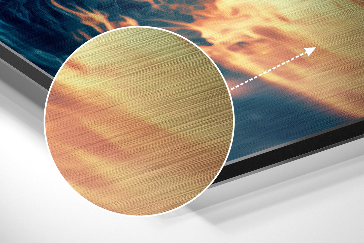 Close-up detail of brushed aluminum surface showing warm orange and gold tones with directional line texture and white circular frame border.