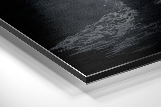 Close-up angled view of layered Dibond panel showing brushed black aluminum surface with embossed lunar landscape and white backing material.