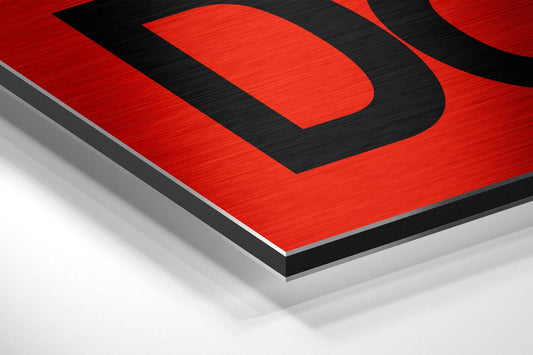 Angled perspective view of red and black brushed aluminum Dibond wall art with layered geometric design and metallic edge detail.