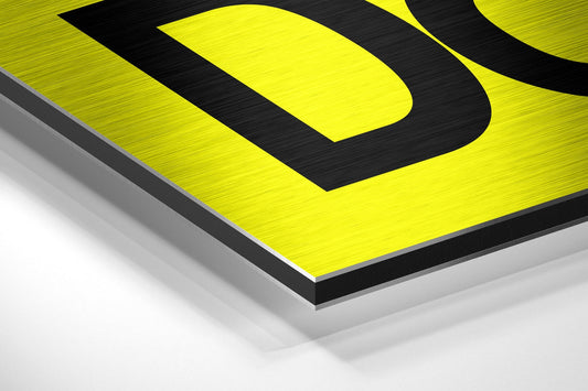 Angled perspective view of yellow and black brushed aluminum wall art with layered edge detail against white background.
