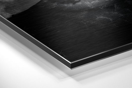 Close-up angled view of layered Dibond panel showing brushed black aluminum surface with white and gray backing layers.