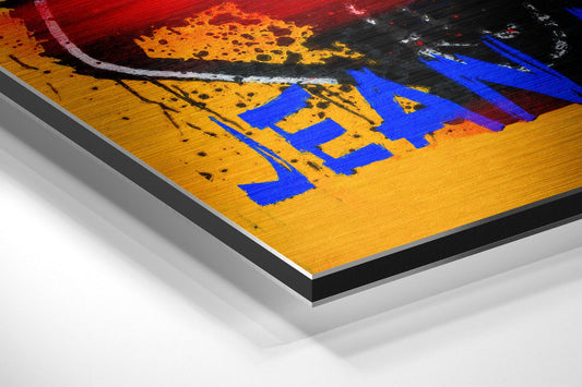 Angled perspective view of yellow skull face aluminum wall art with blue letters and red/orange background showing layered mounting system.