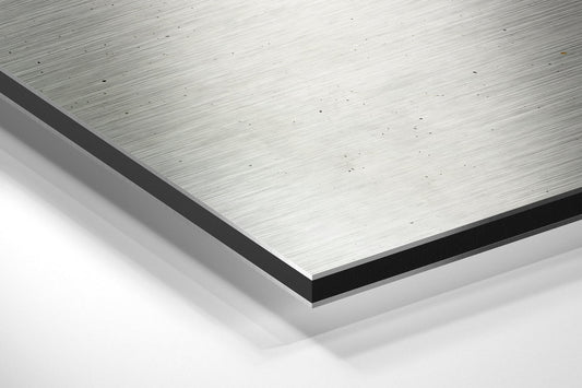 Close-up angled view of brushed aluminum Dibond panel showing layered edge construction with black border and white backing.