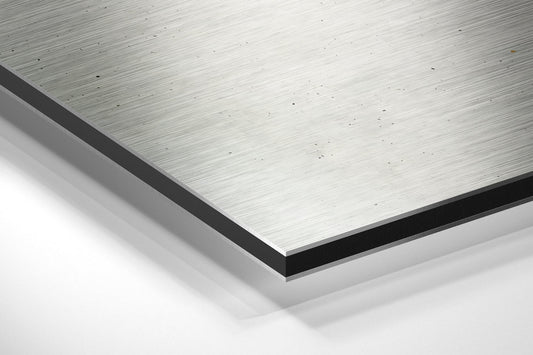 Close-up angled view of brushed aluminum Dibond panel edge showing layered construction with black core and silver metallic surface finish.
