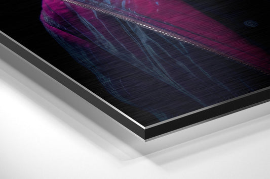 Close-up angled view of layered aluminum dibond panel edges showing magenta, blue, and black printed surface with metallic silver border detail.