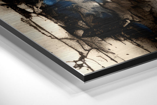 Close-up angled view of brushed aluminum Dibond wall art with black frame edge, showing tree branch shadows on light wood surface.