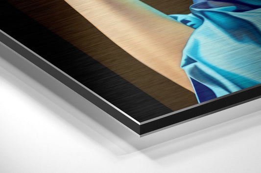 Close-up angled view of layered aluminum dibond print edge showing brushed metal finish with turquoise and blue turban detail visible.