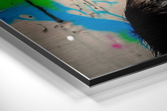 Close-up angled view of brushed aluminum Dibond print edges showing layered metal frame with colorful graffiti art of chimp wearing headphones visible on surface.