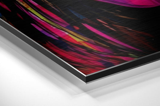 Angled perspective view of brushed aluminum-framed pop art print showing colorful diagonal streaks in magenta, yellow, and blue on black background.