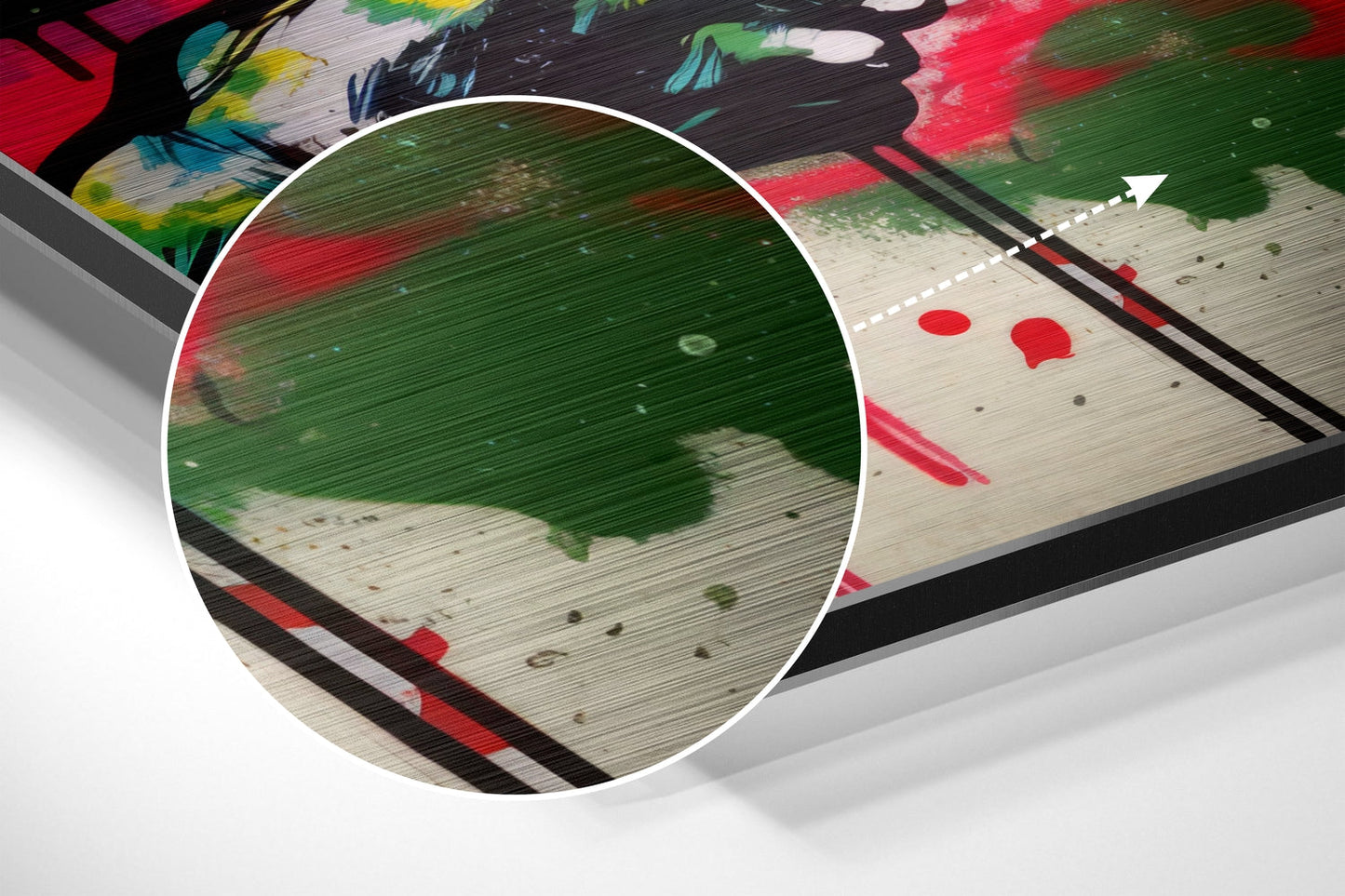 Close-up magnified view of brushed aluminum surface showing green and red paint strokes with scattered spatter details.