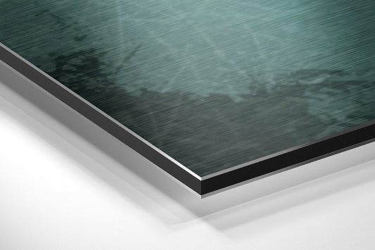 Close-up angled view of layered aluminum dibond panel showing teal brushed metal surface with black edge trim and white backing.