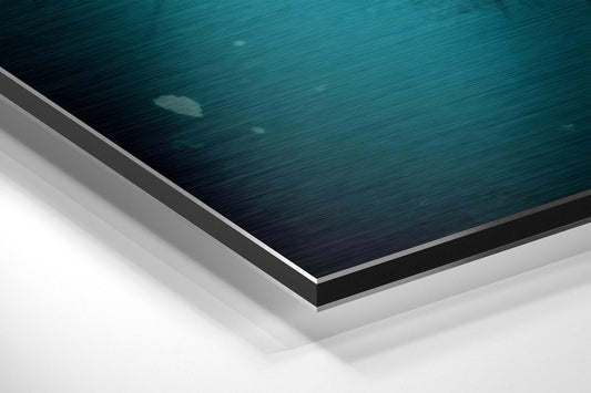 Close-up angled view of layered aluminum dibond panel edges showing teal brushed surface with gray and white backing layers.