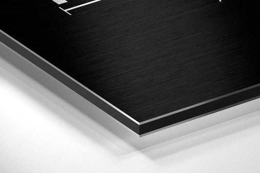 Close-up angled view of layered black brushed aluminum and white composite materials showing edge detail and surface texture.