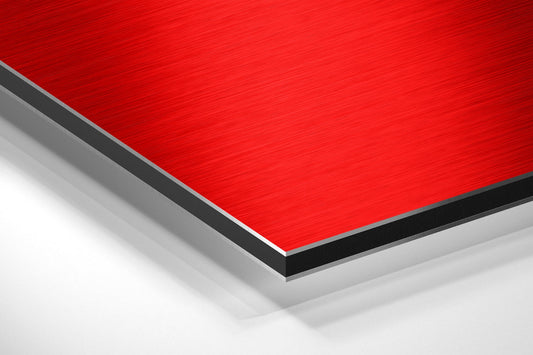 Angled perspective view of layered red, black, and gray brushed aluminum composite panel showing edge detail and surface texture.